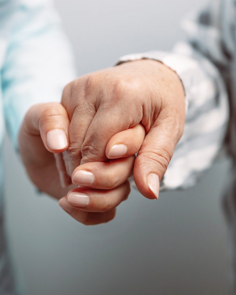 Caregiver, carer hand holding elder hand in hospice care background, closeup. Happy mother's day.
